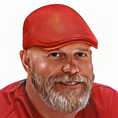 John Dean smiling and wearing a red shirt and driving cap.